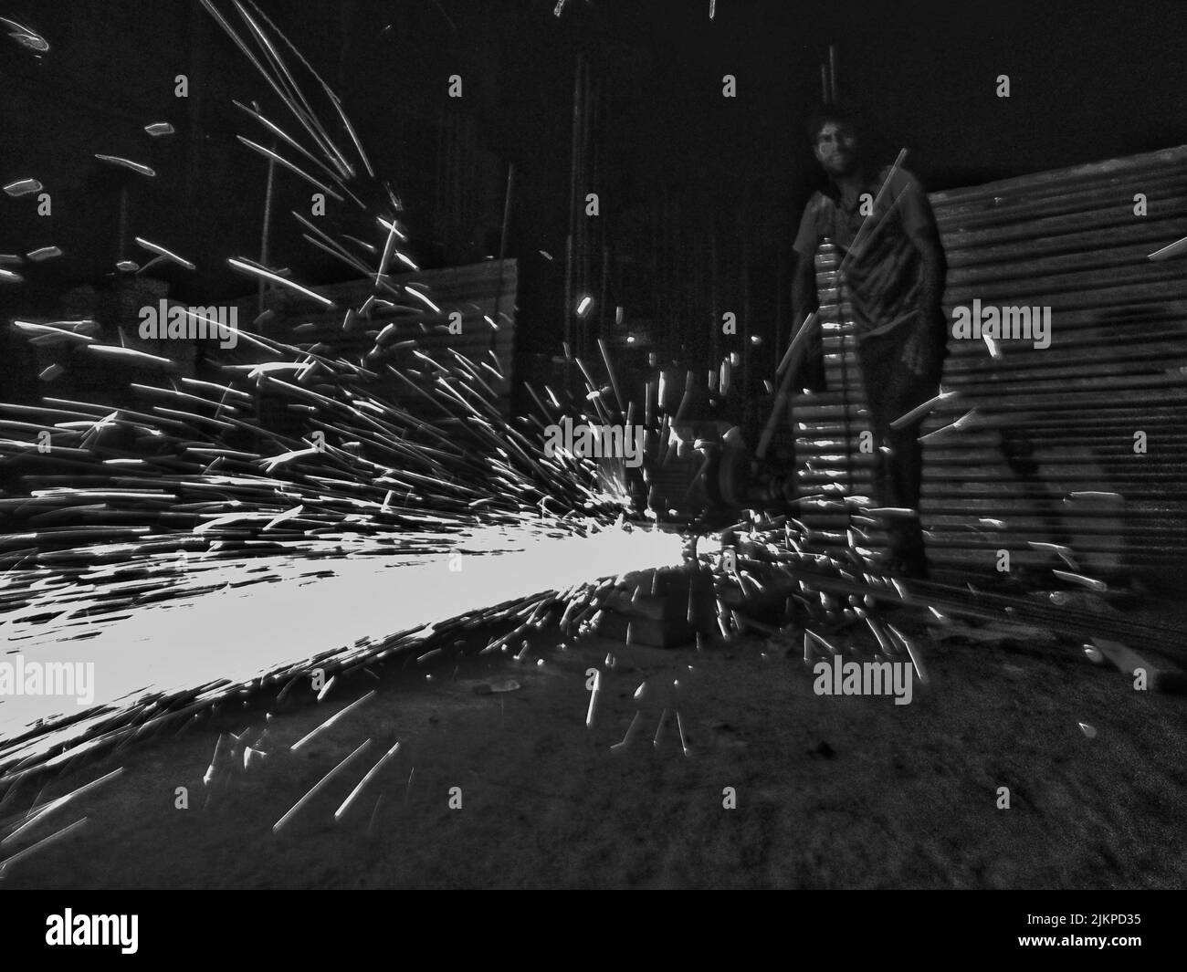A scene of rod cutting with machine at night, causing sparks, at night. Grey style. Stock Photo