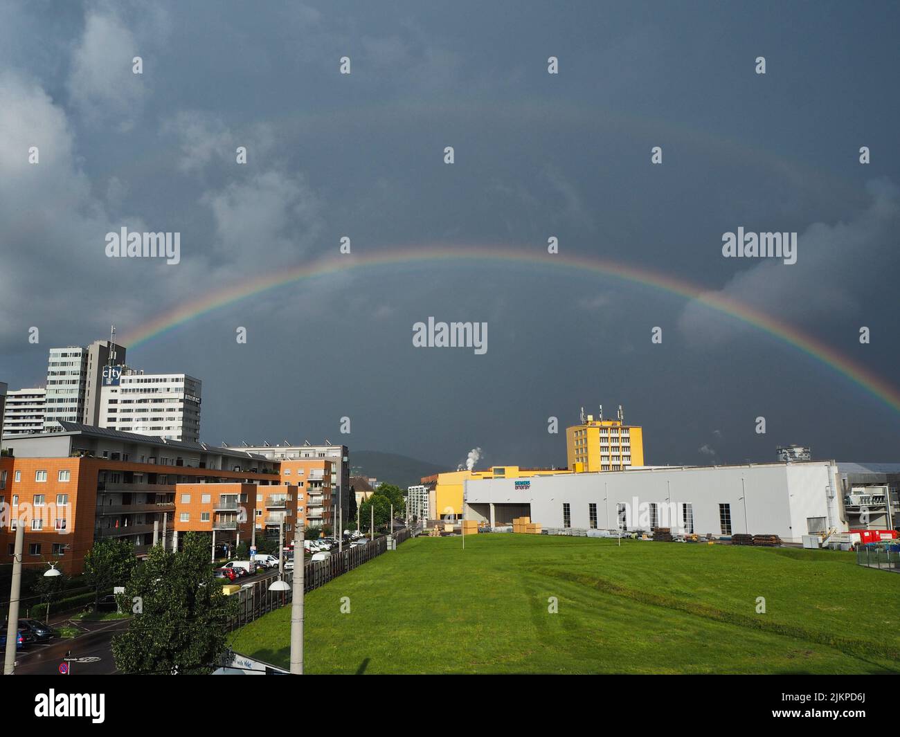 beautiful rainbow over the Siemens building in the city of Linz, Austria. Rainy weather with dramatic clouds and rainbow in the city Stock Photo