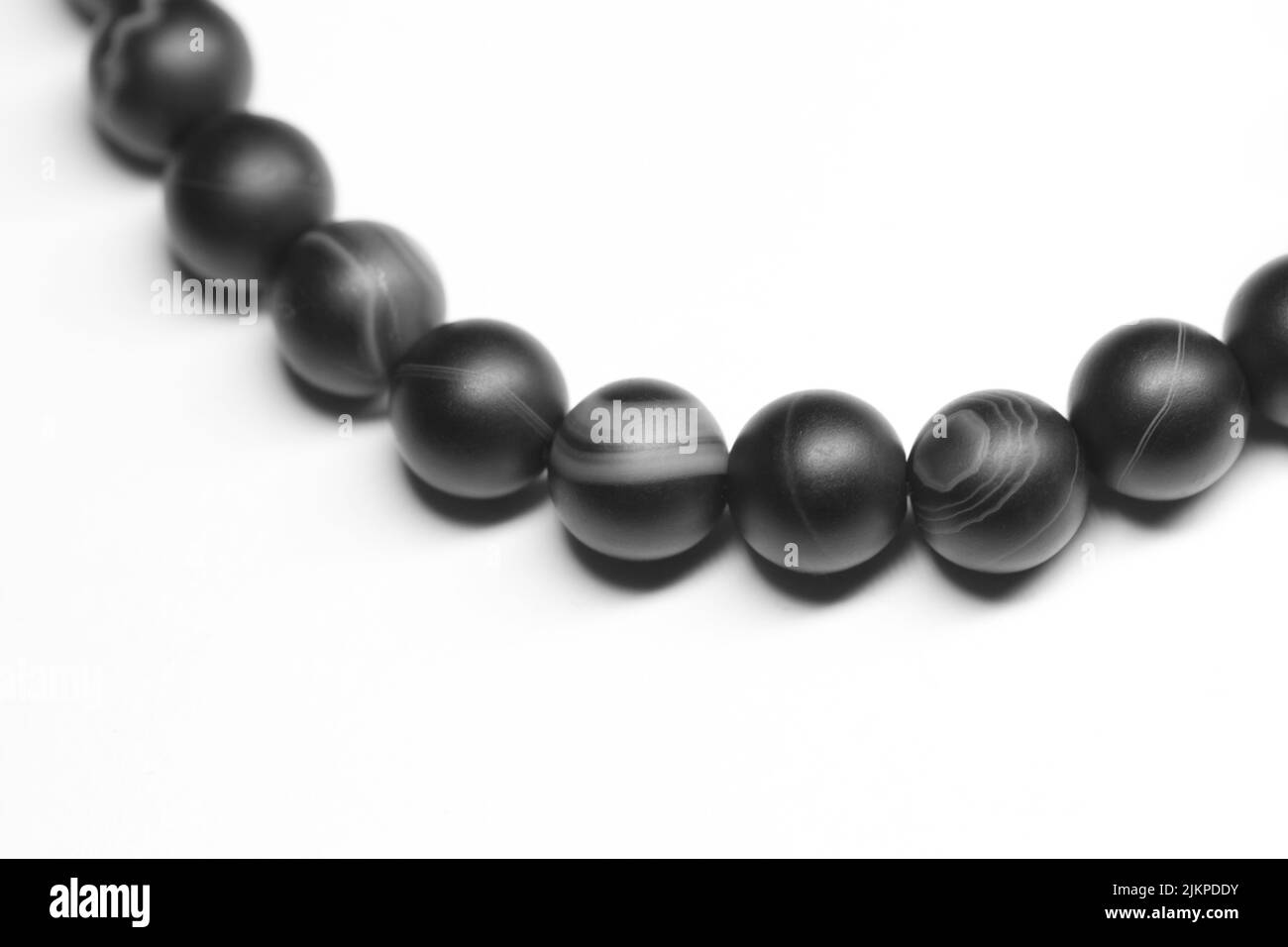 Bracelet of round black agate beads isolated on white background, close-up photo with selective focus Stock Photo