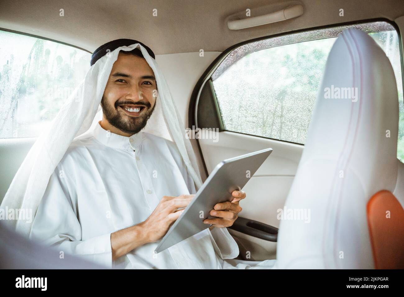 man wearing turban using a pad while sitting on his car Stock Photo