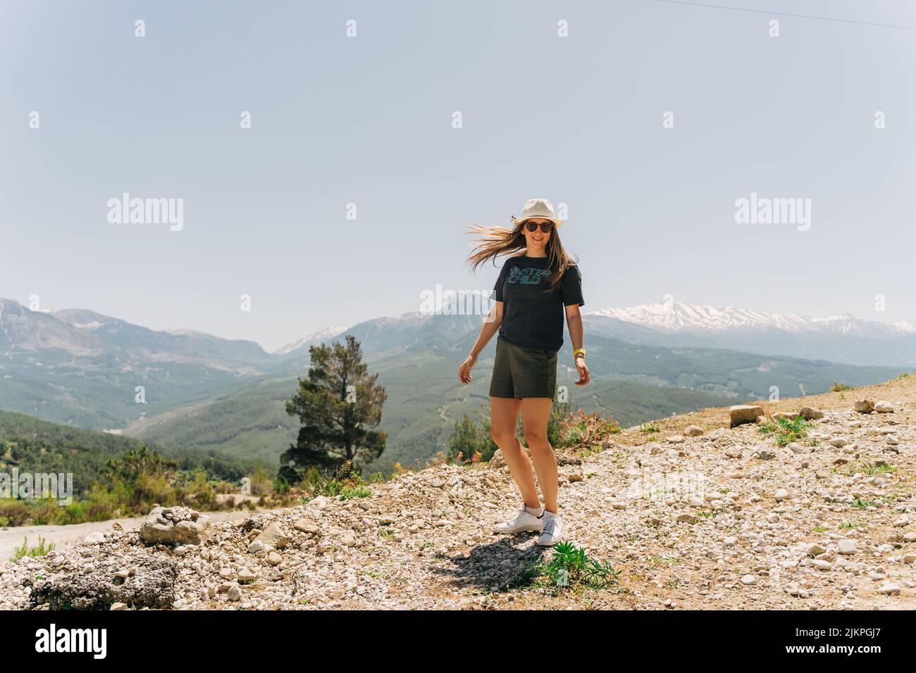 Young woman in hat standing on Mountain View Stock Photo