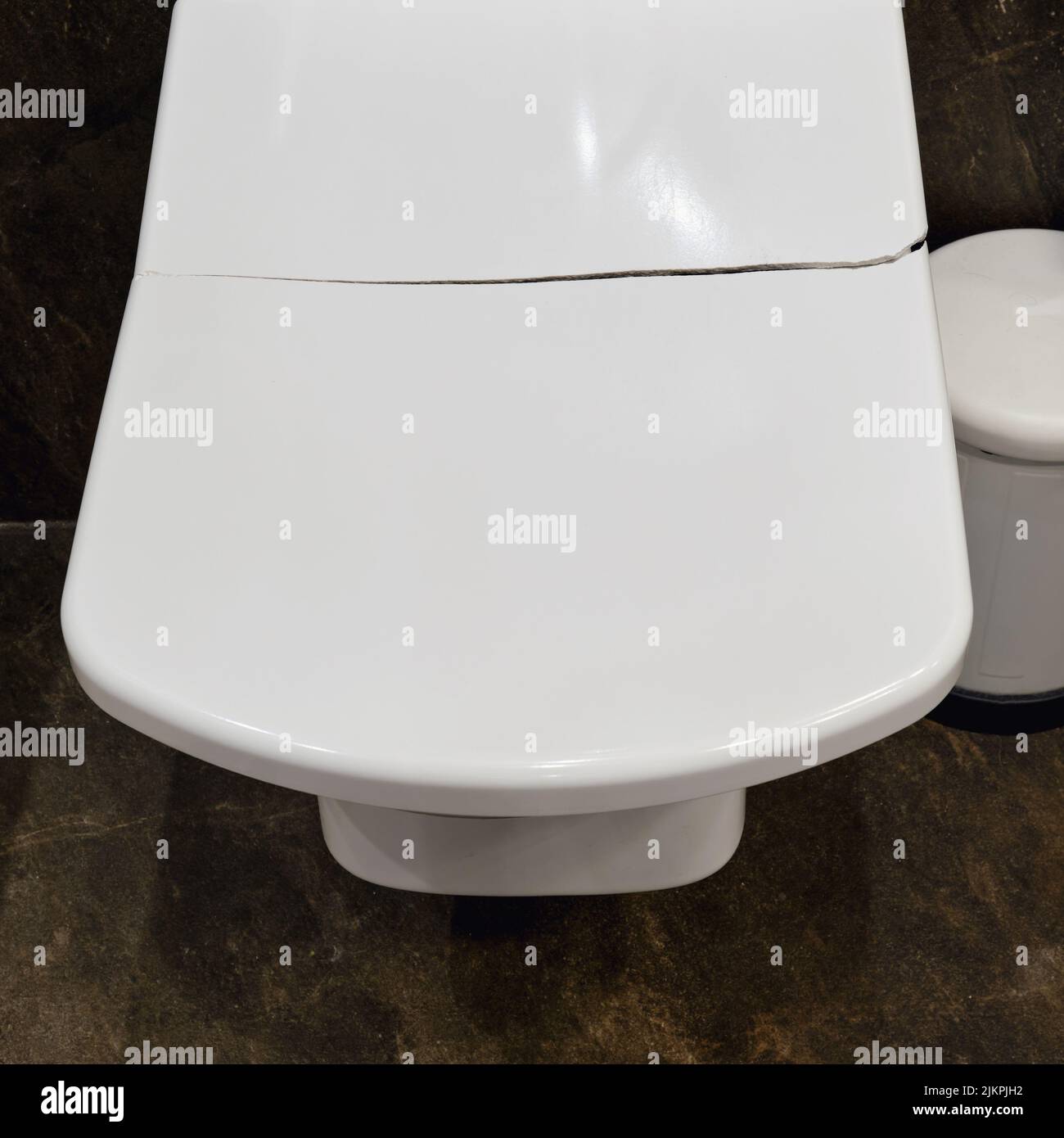 Cracked white toilet lid. A broken closing lid in the home toilet Stock