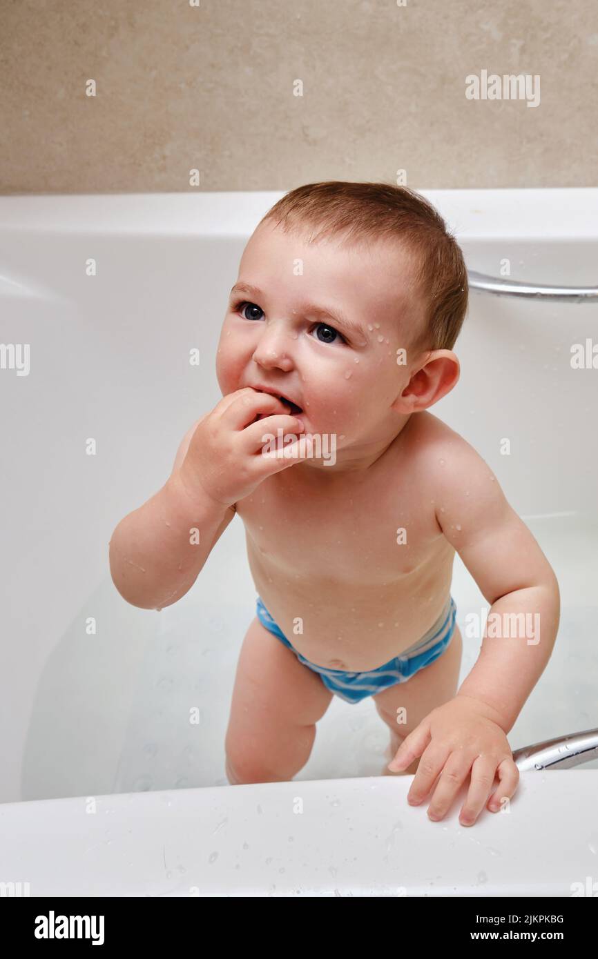 Toddler baby boy the bathtub. A smiling child plays in the water of a