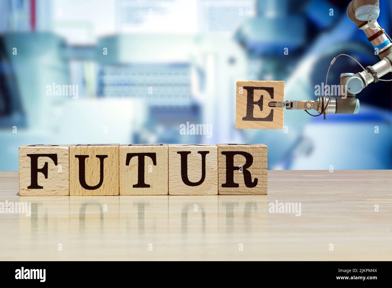 Industrial gripping robot picking wooden letter for build message on wooden desk and machine blue tone color on blurred background Stock Photo