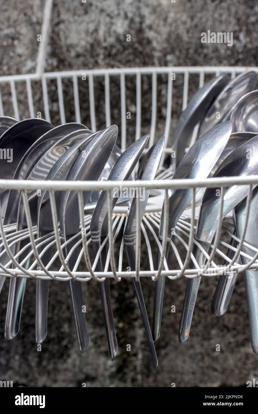 Aluminum spoons are dried in a grate drip tray hang on the wall Stock