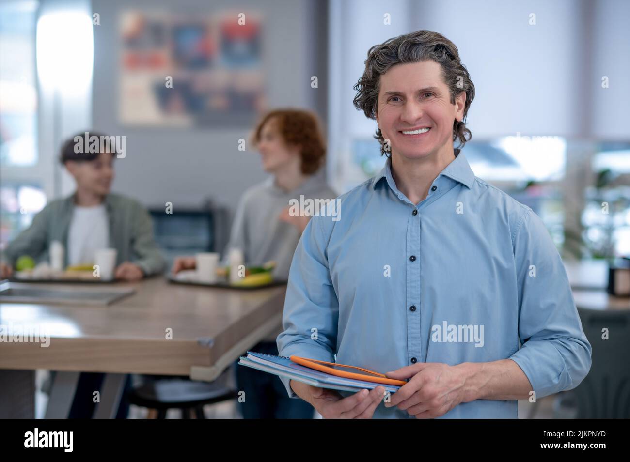 A smiling male teacher in a school canteen Stock Photo