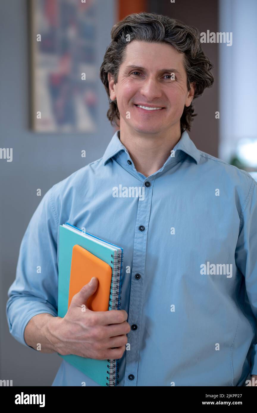 Smiling man in a blue shirt with tablet and notebook Stock Photo