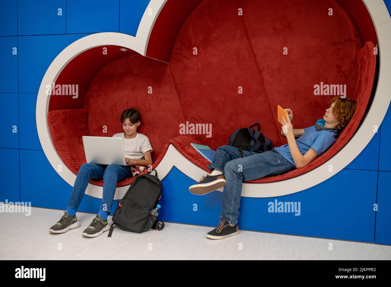 Two school boys feeling comfortable in the lounge zone and doing homework Stock Photo
