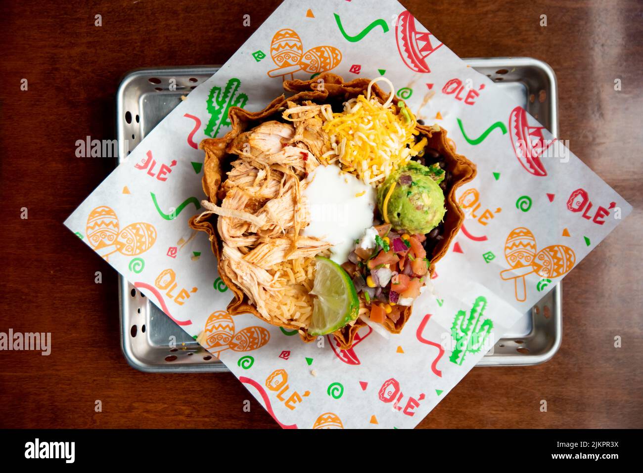 A top view of a Mexican chicken bowl with beans, lettuce, pico de gallo