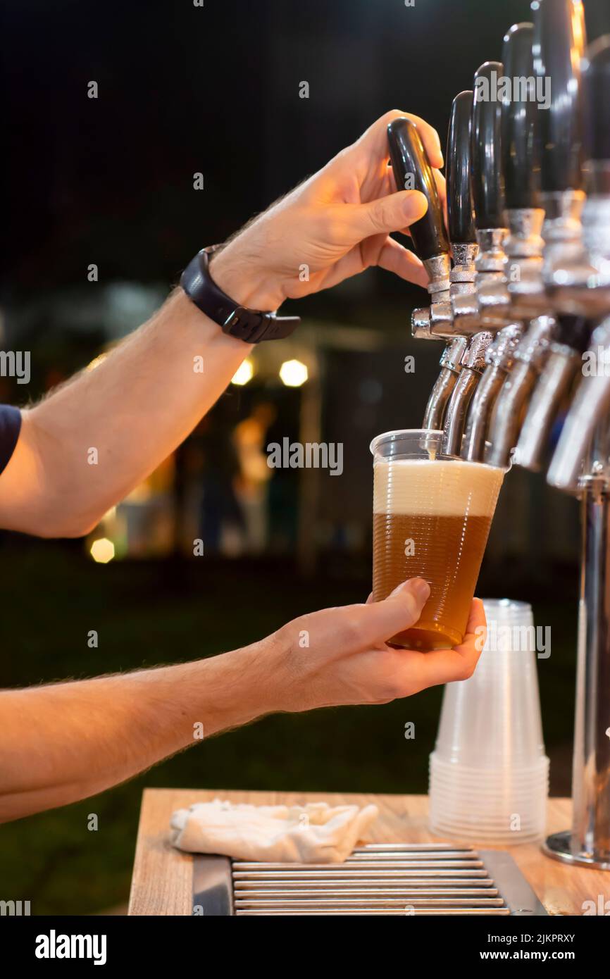 A male's hands pouring beer in a plastic cup from a kegerator Stock