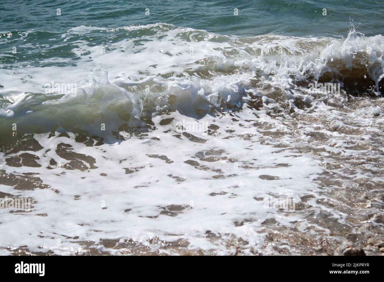 The foam waves hitting a sandy seashore of a beach Stock Photo - Alamy