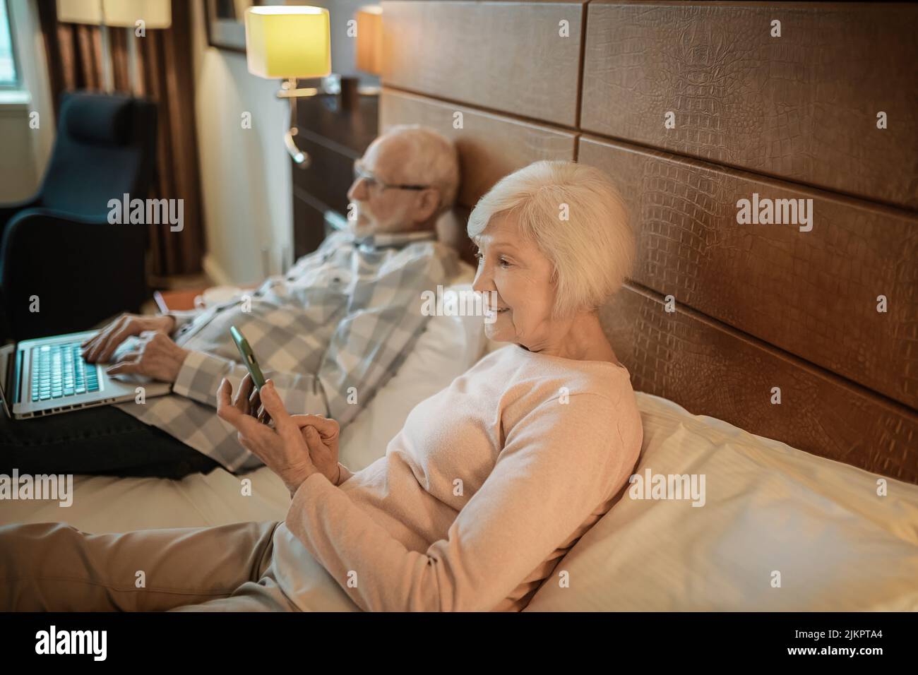 Senior couple lying in bed and watching something online Stock Photo