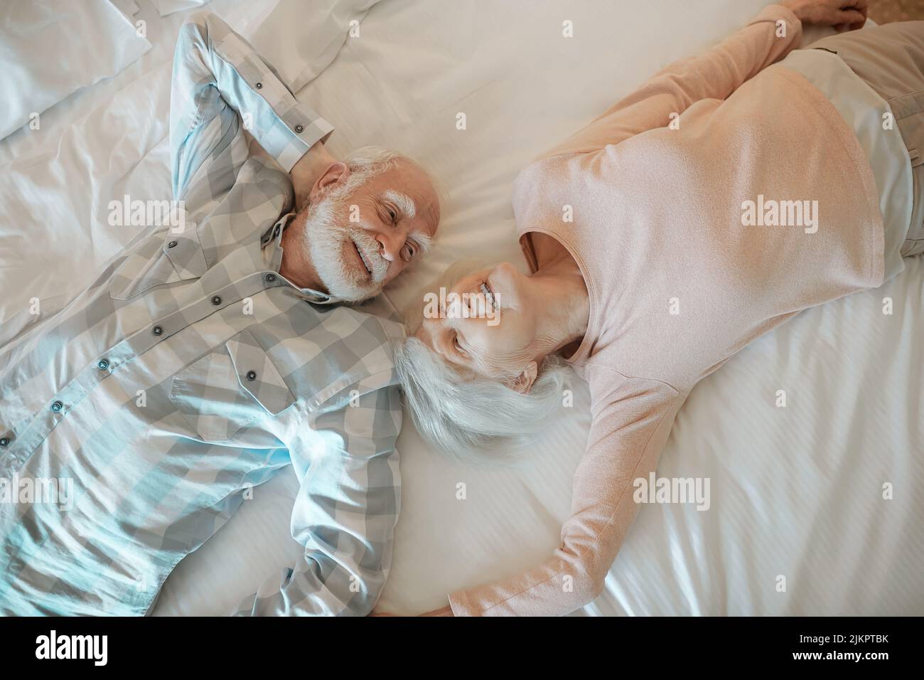 Two senior people lying on bed and looking relaxed Stock Photo