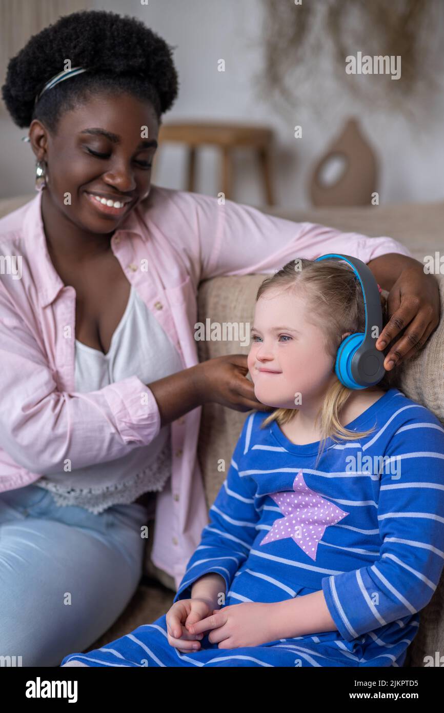 African american woman putting headphones on a girls head Stock Photo