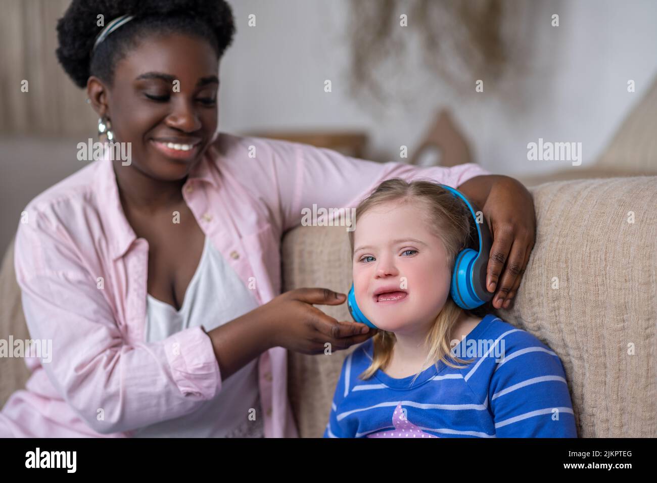 African american woman putting headphones on a girls head Stock Photo
