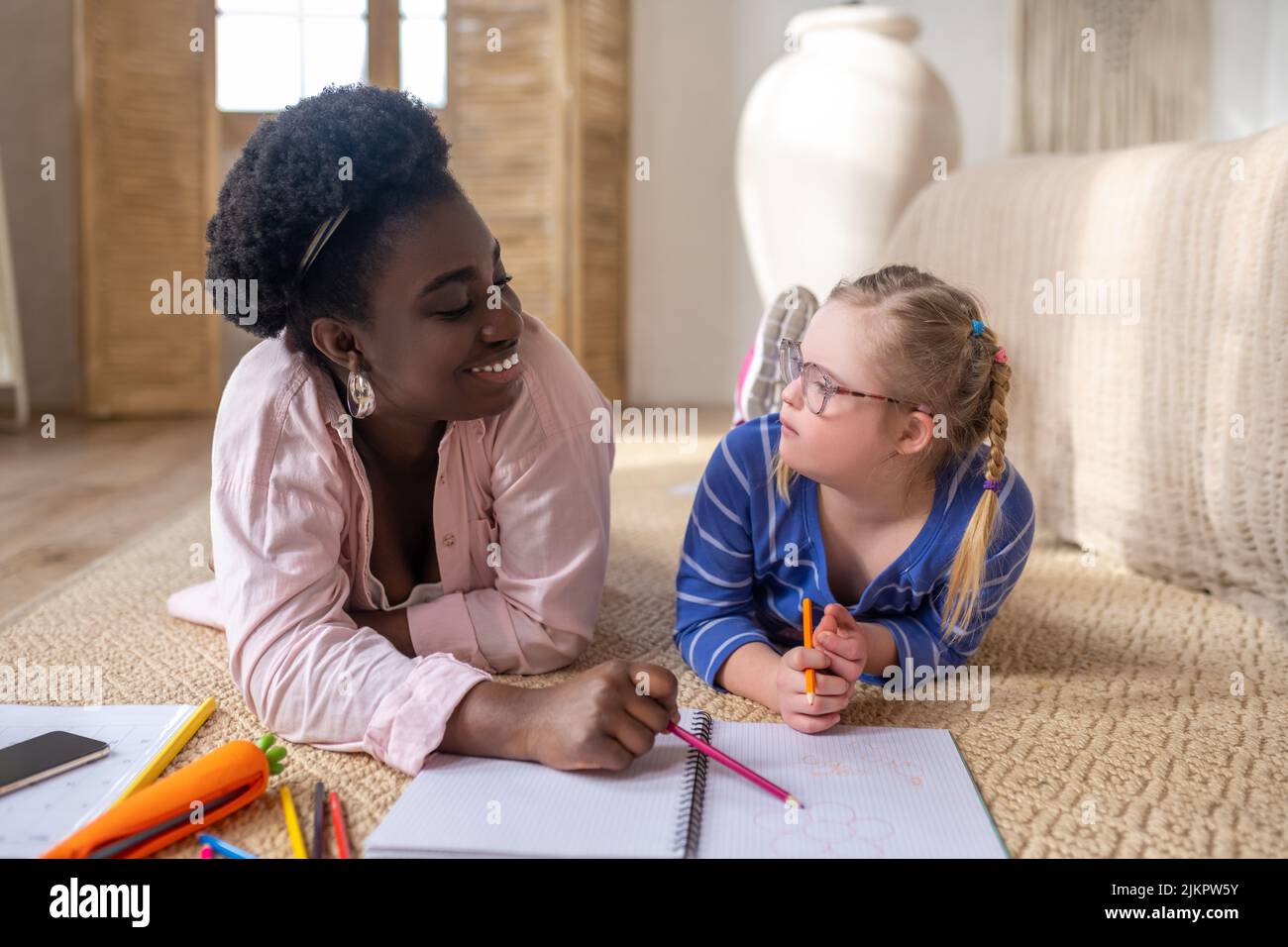 A girl in eyeglasses looking at her teacher whule studying at home Stock Photo