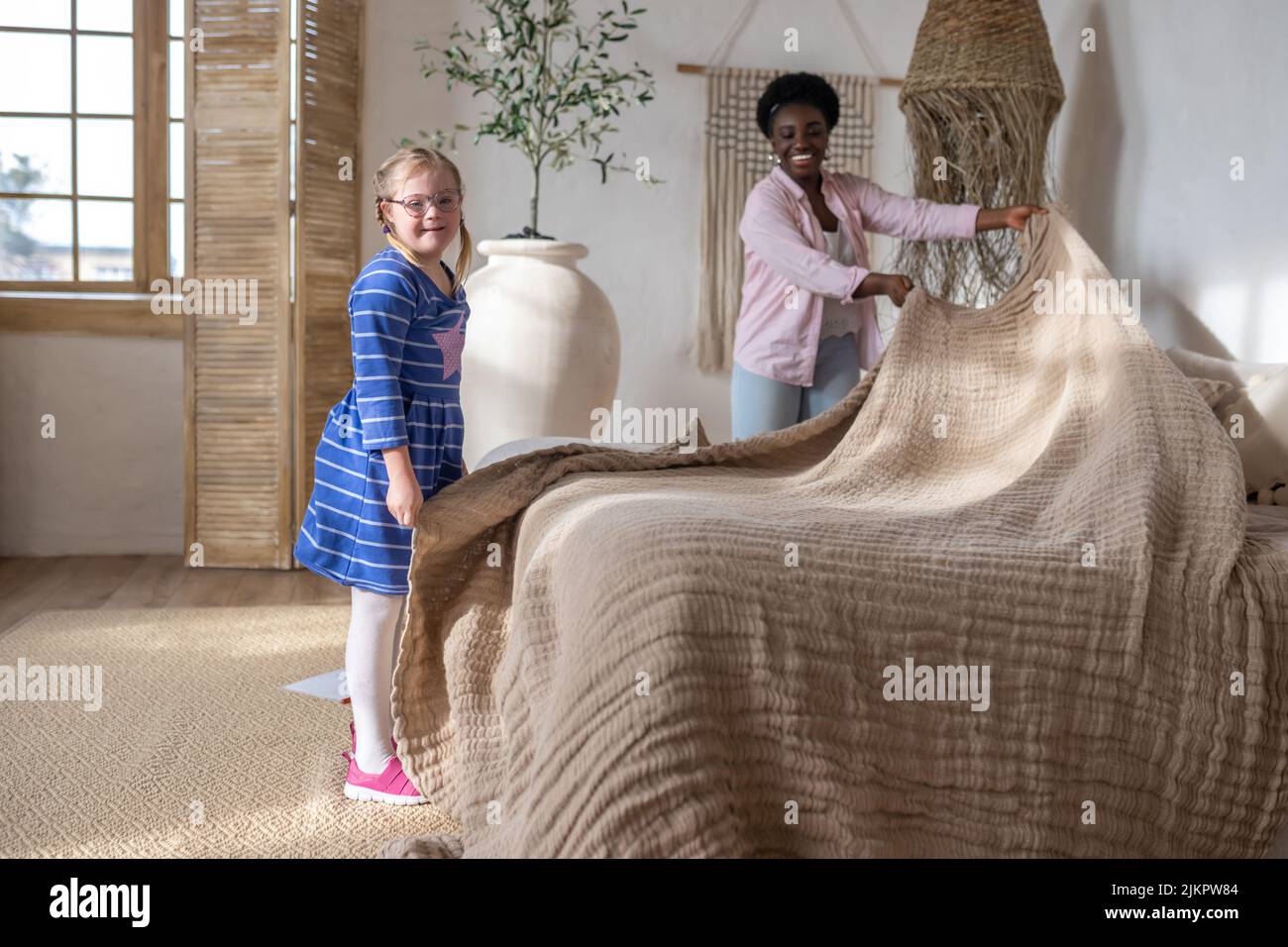 A woman and a girl making bed in the morning Stock Photo
