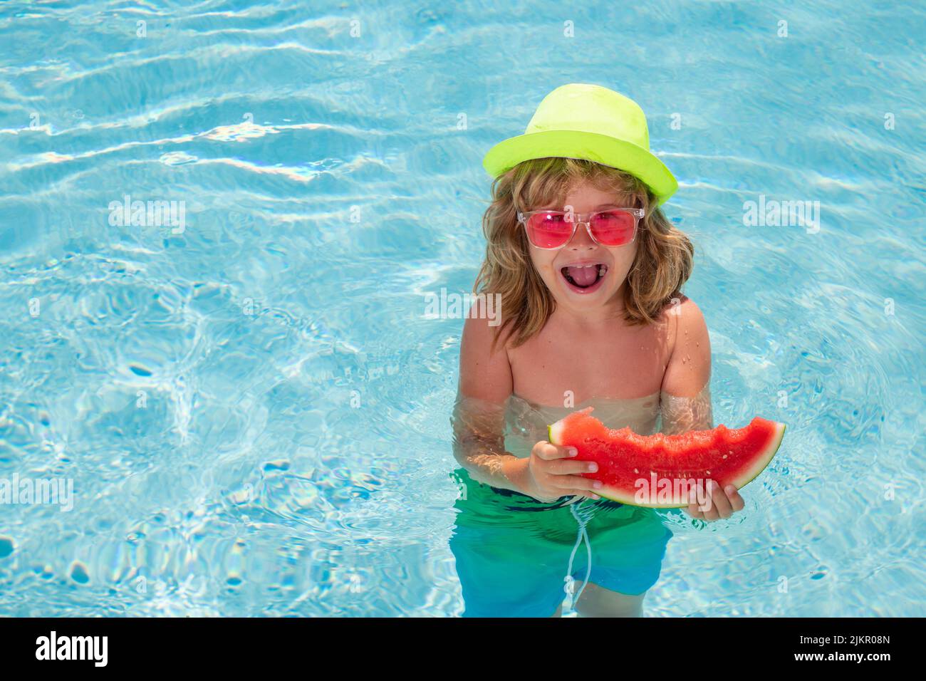 Child eating watermelon in swimming pool. Active healthy lifestyle