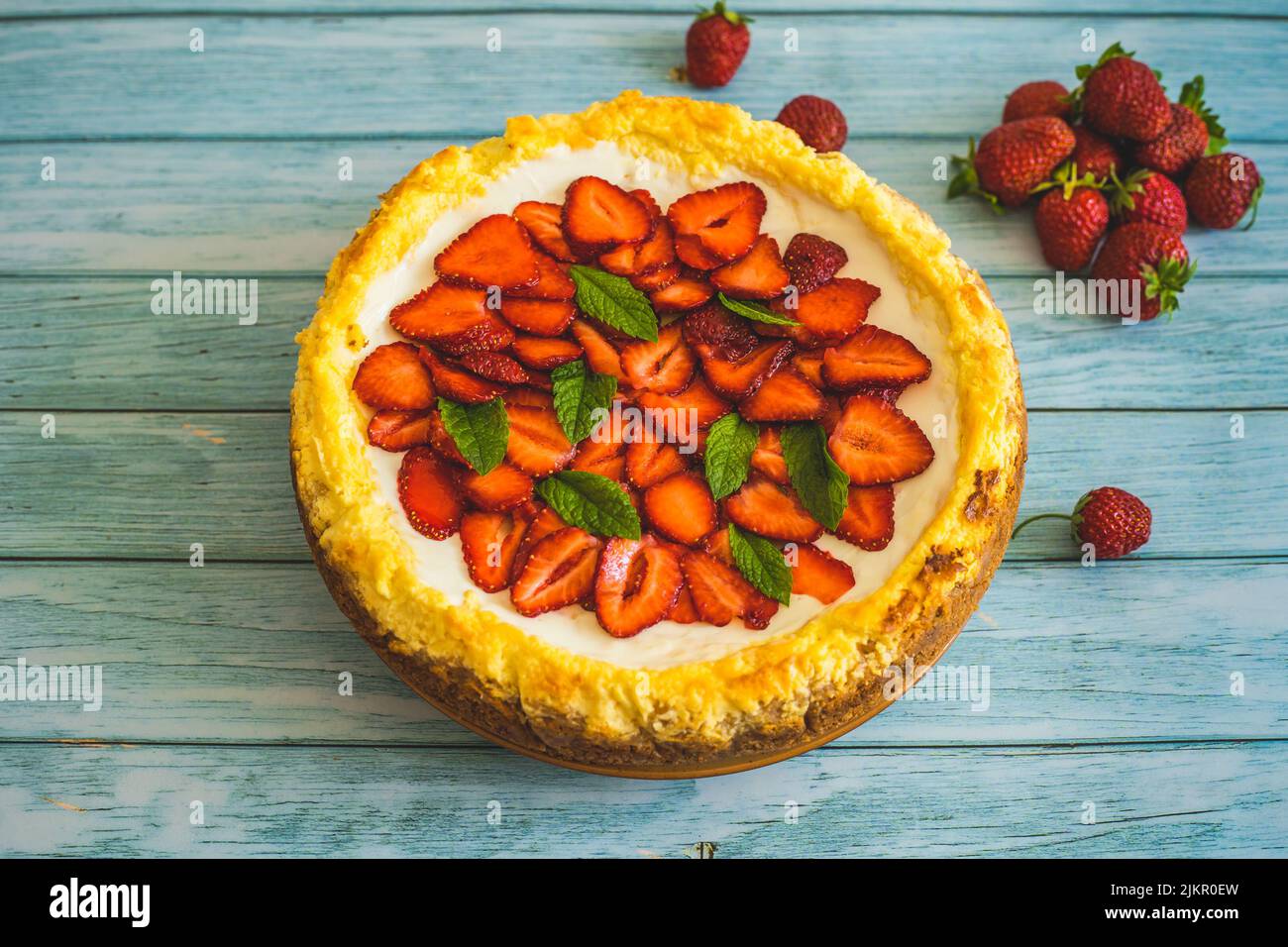 Strawberry homemade cake on wooden table.Delicious cheesecake with strawberries decorated with mint leaves.Top view.Healthy organic summer berry desse Stock Photo