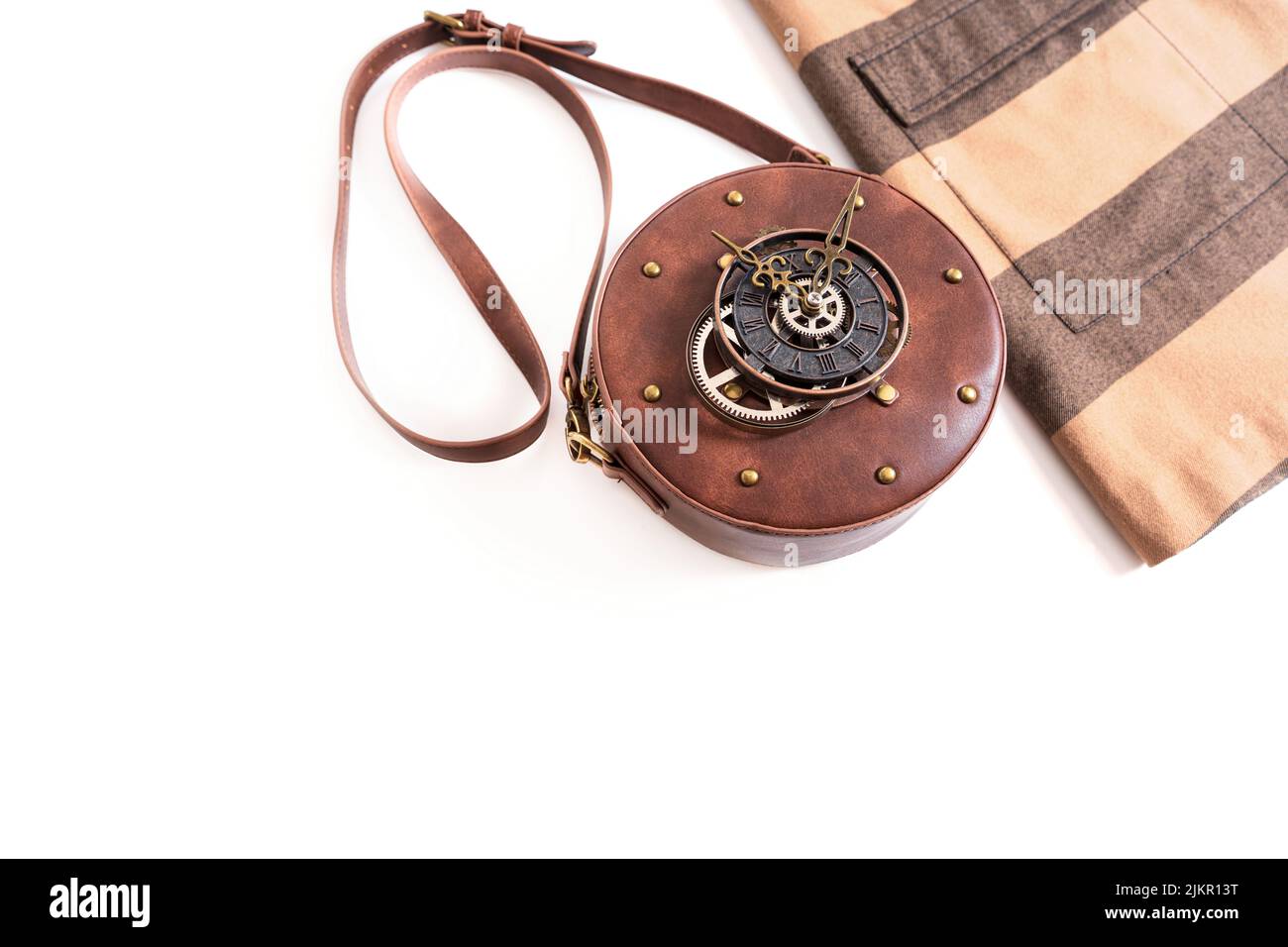 Dress and a steampunk style leather circle bag with rivets and a clock mechanism isolated on white background with copy space. Stock Photo