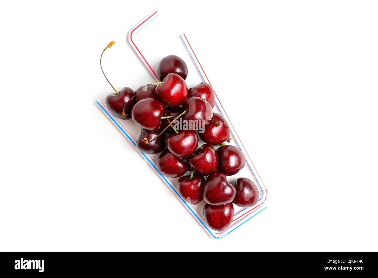 Creative cherry cocktail flat-lay made from sweet cherries and drinking straws isolated on white background with copy space. Stock Photo