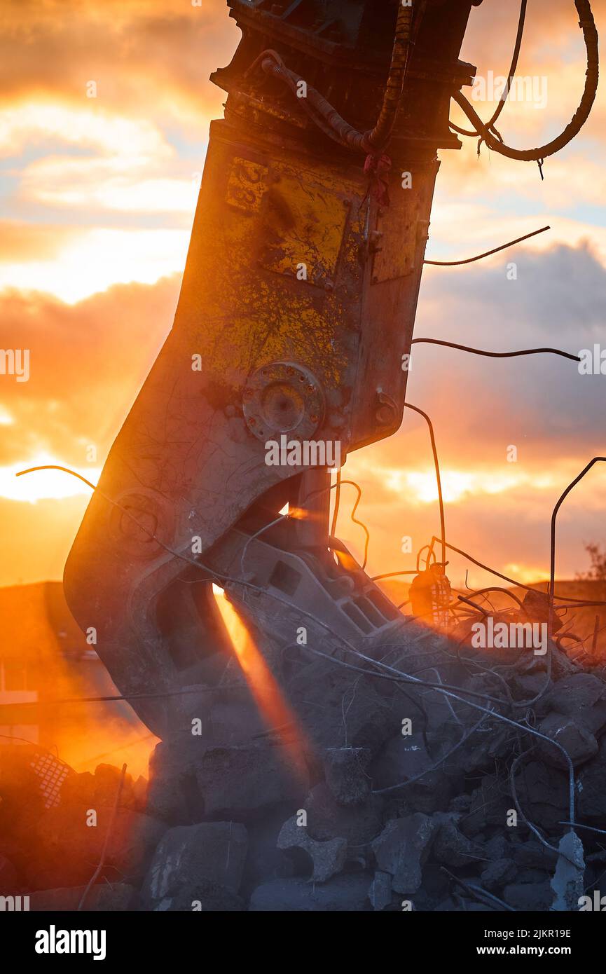 Modern crusher on excavator rigging dismantles concrete beam Stock