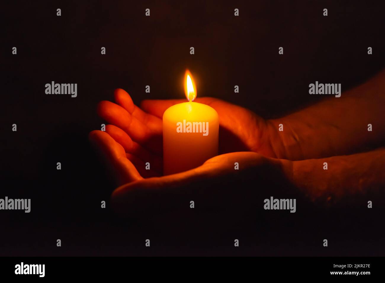 Burning candle in a mans hand religion concept.Candle in hands on a