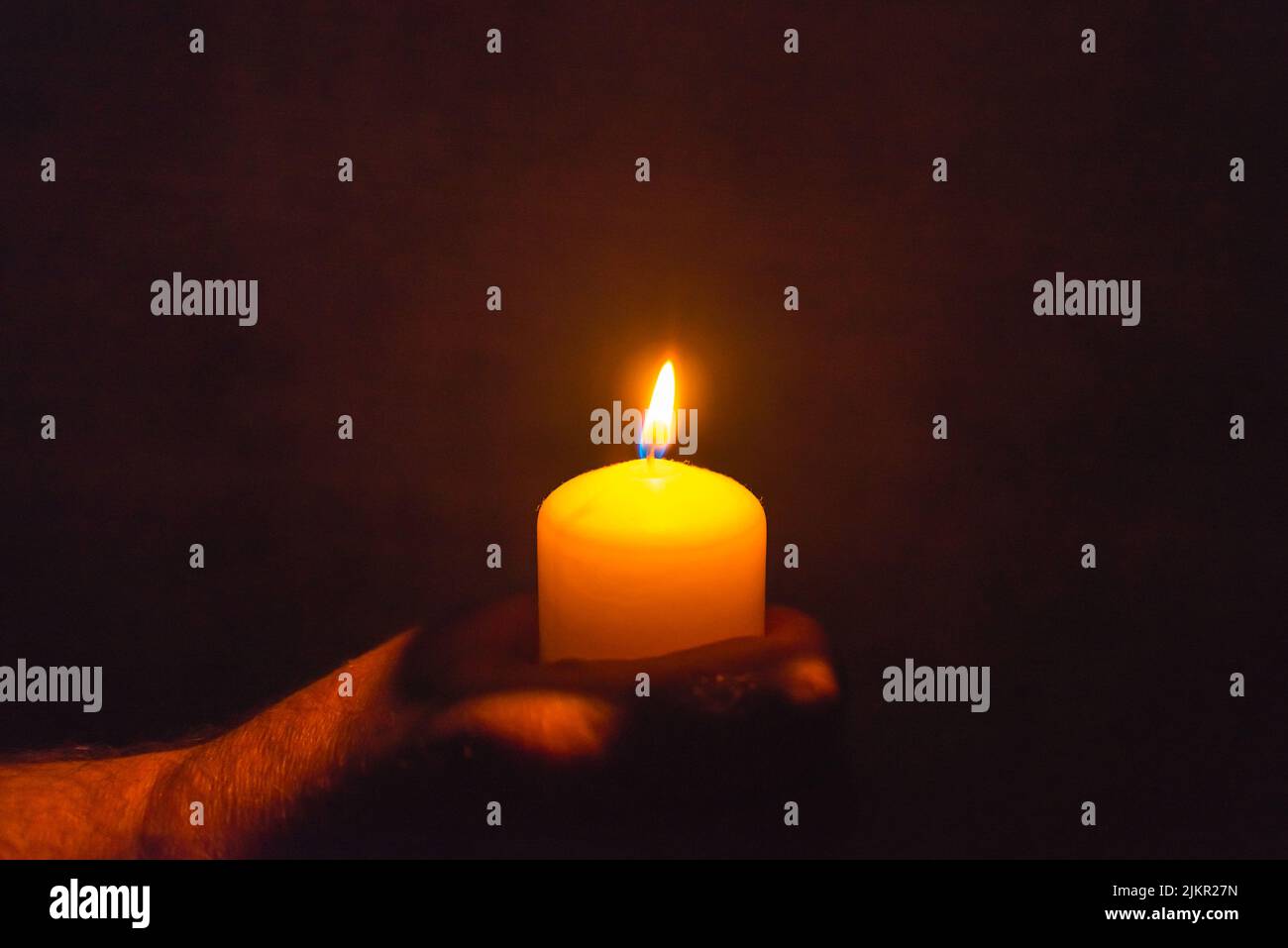 Burning candle in a mans hand religion concept.Candle in hands on a