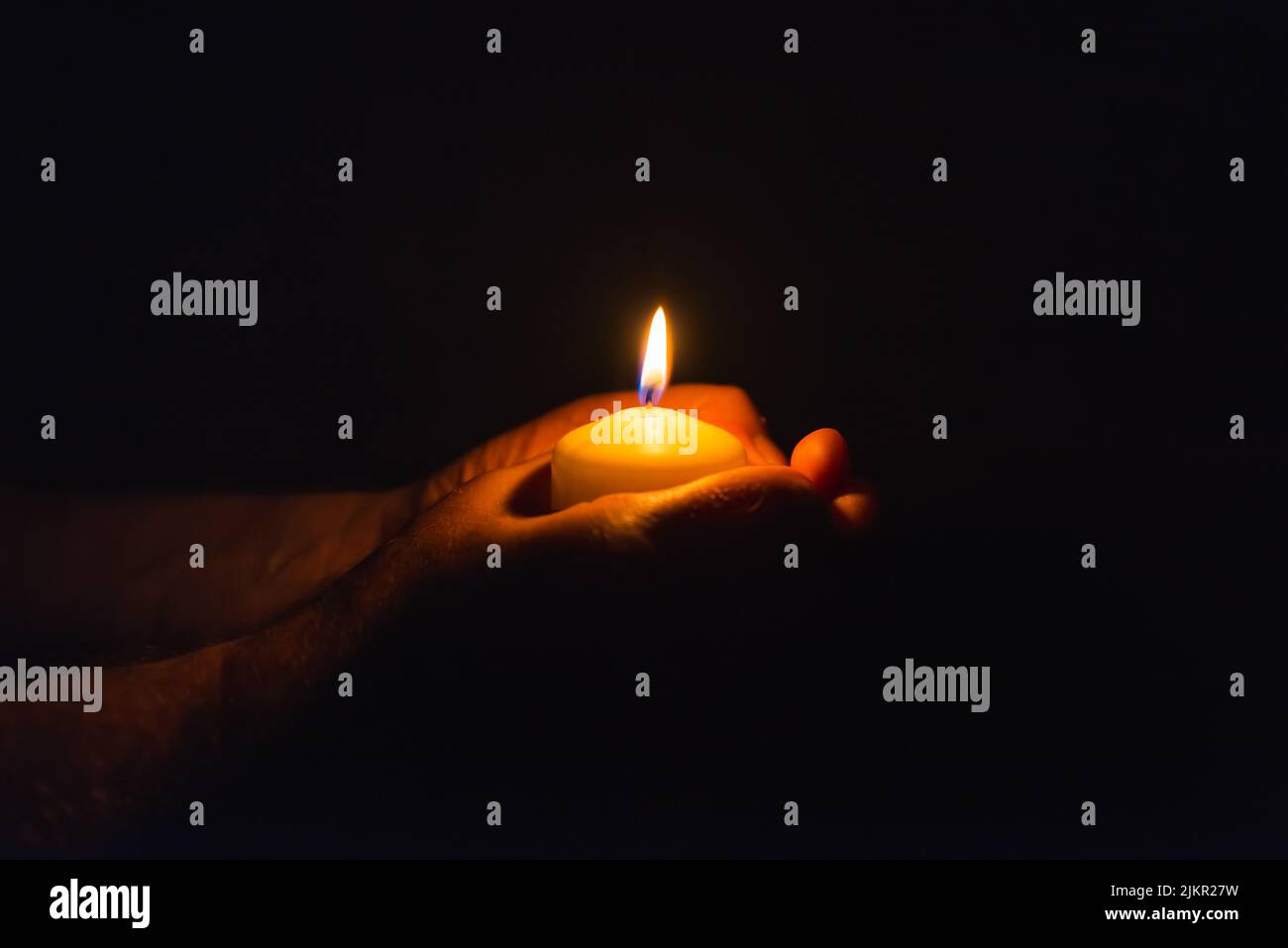 Burning candle in a mans hand religion concept.Candle in hands on a dark background Stock Photo