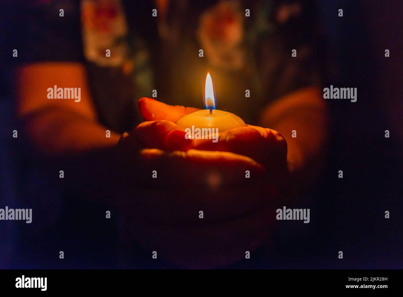 Candle in female hands on black dark background.Prayers candle in hands