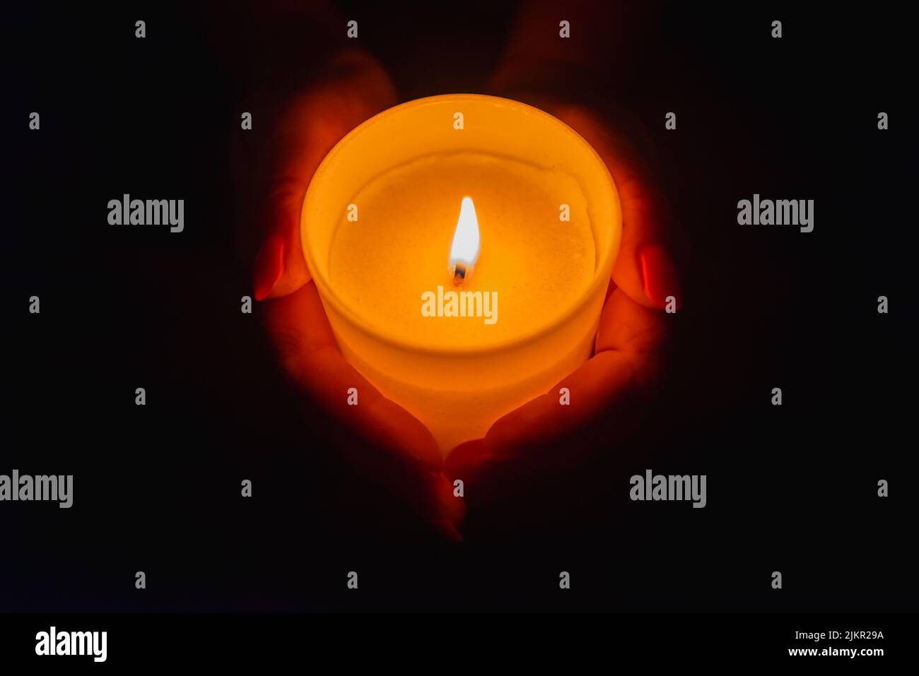 Candle in female hands on black dark background.Prayers candle in hands