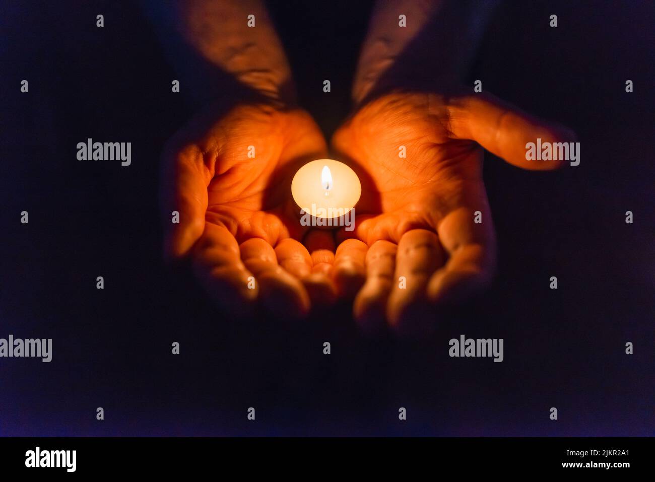 Burning candle in a mans hand religion concept.Candle in hands on a