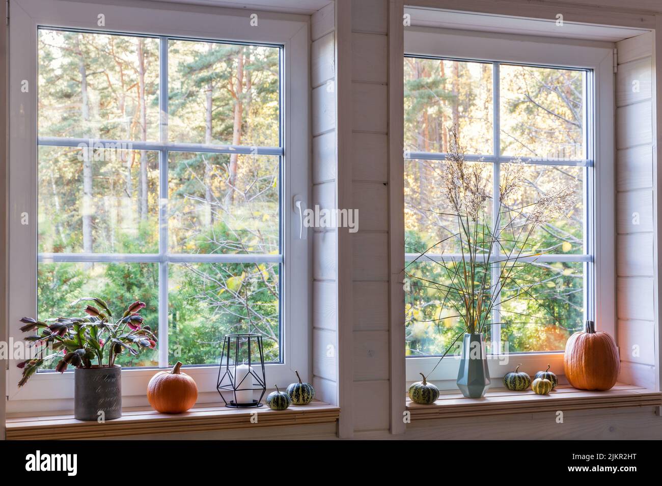 Orange pumpkins on windowsill, candles, autumn leaves and lantern. Scandinavian style Stock Photo