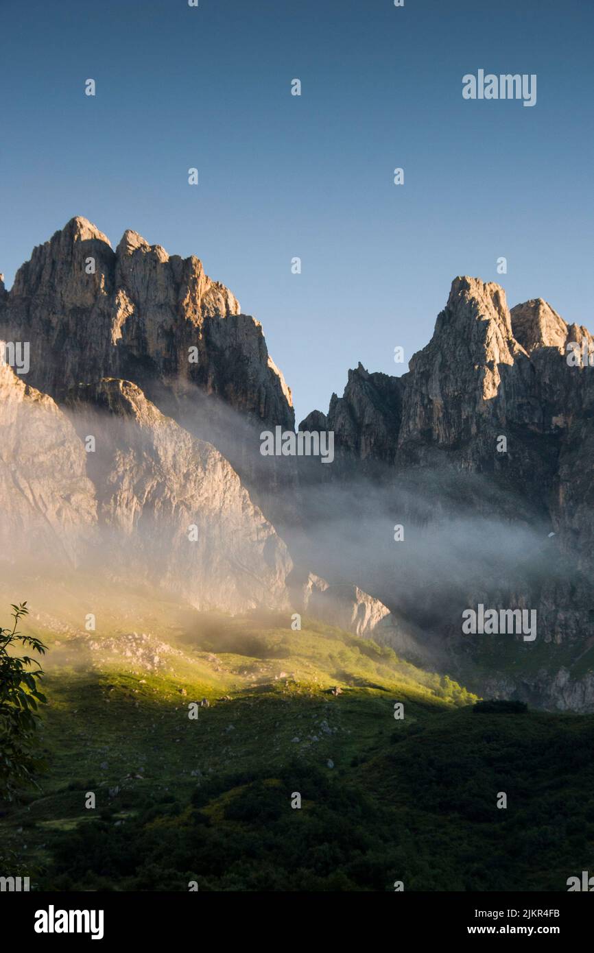 The morning clouds hover over the mountain rocky peaks in a soft light image Stock Photo