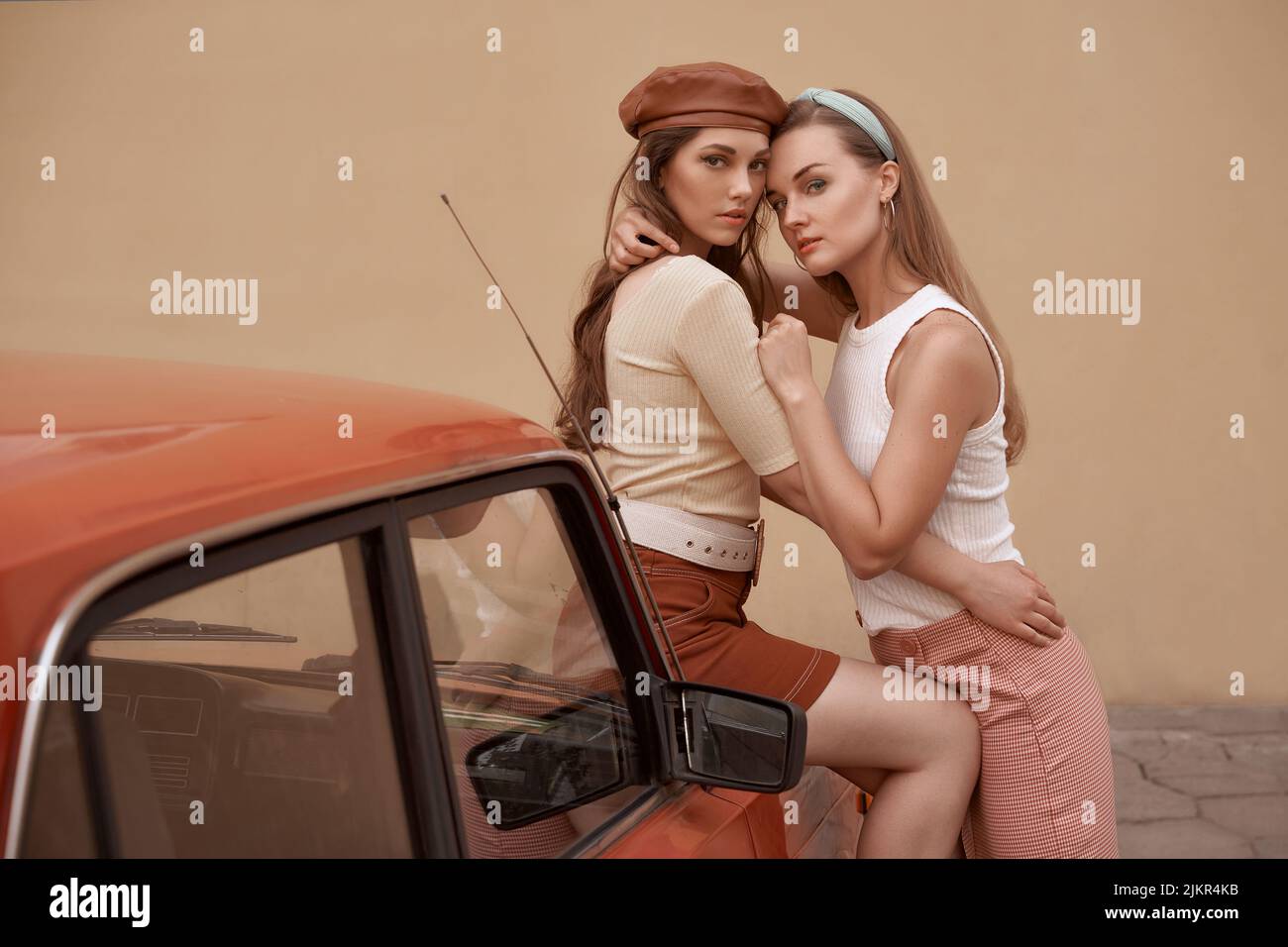 Young beautiful models dressed in retro vintage style enjoying the old european city summertime lifestyle. Old fashioned clothes. Stock Photo