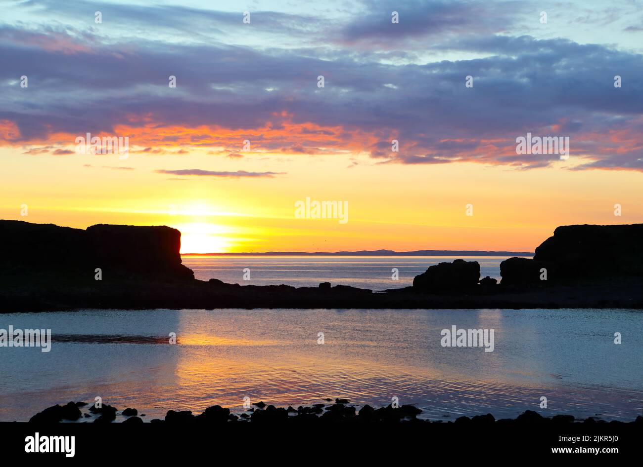 Sunset from Lunga in the Treshnish Isles of Scotland looking towards the Isle of Coll in the far distance Stock Photo