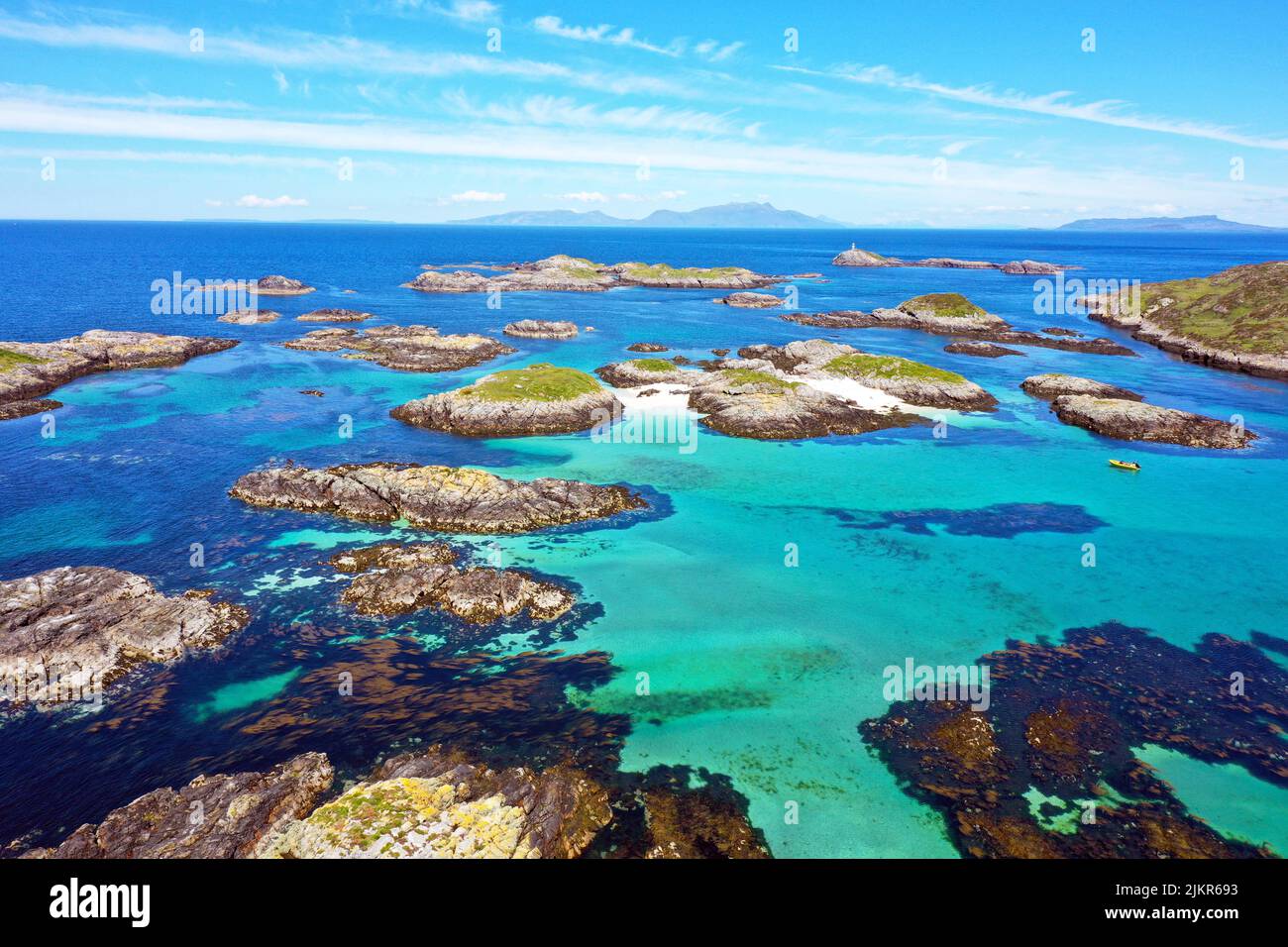 Aerial view of the Cairns of Coll, Inner Hebrides of Scotland with the islands of Rum and Eigg in the background and Sùil Ghorm with the lighthouse Stock Photo