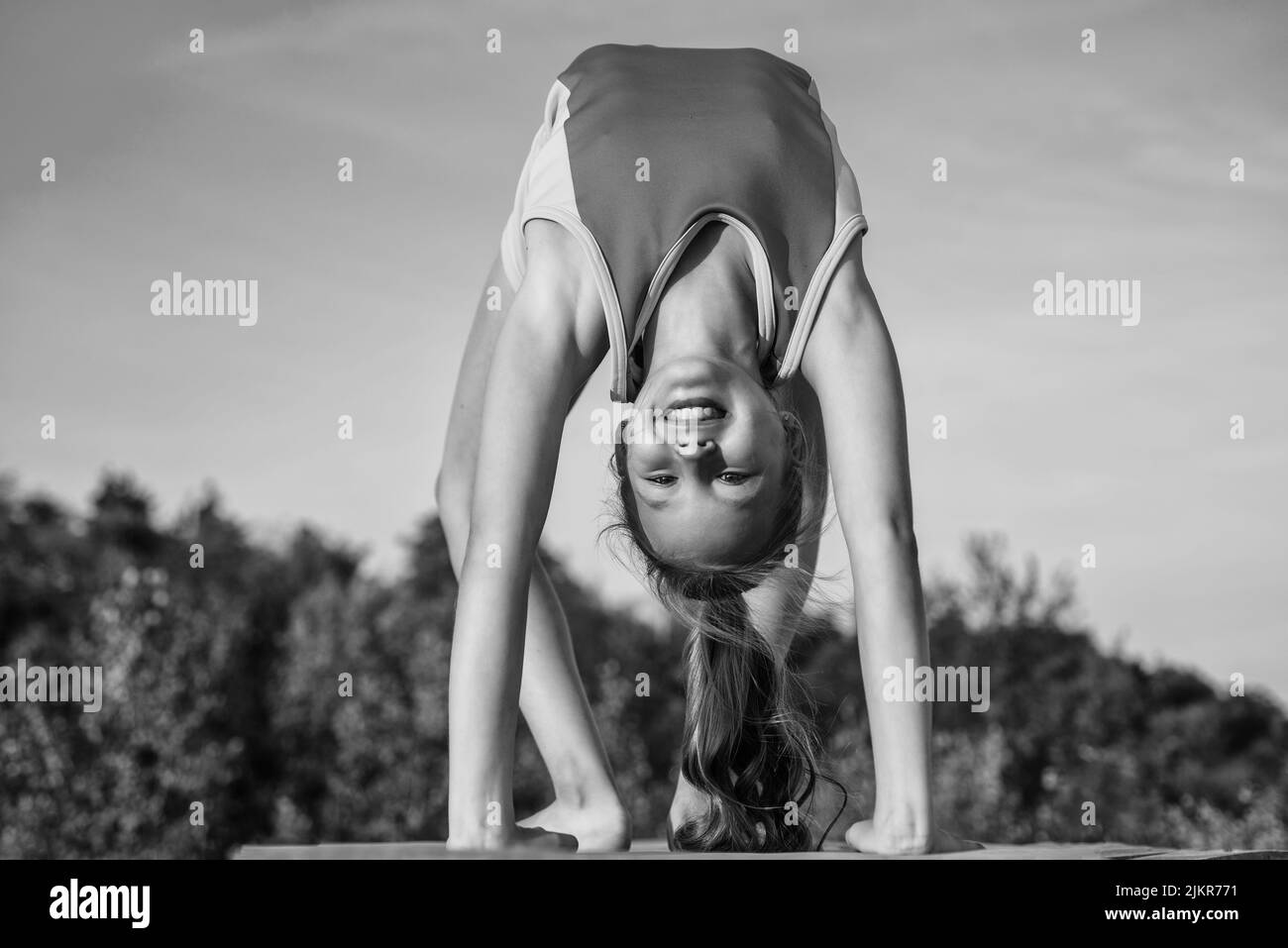 Happy and sporty. happy teen girl in handstand. kid has flexible body. child in sport clothes training. concept of stretching and warming up Stock Photo