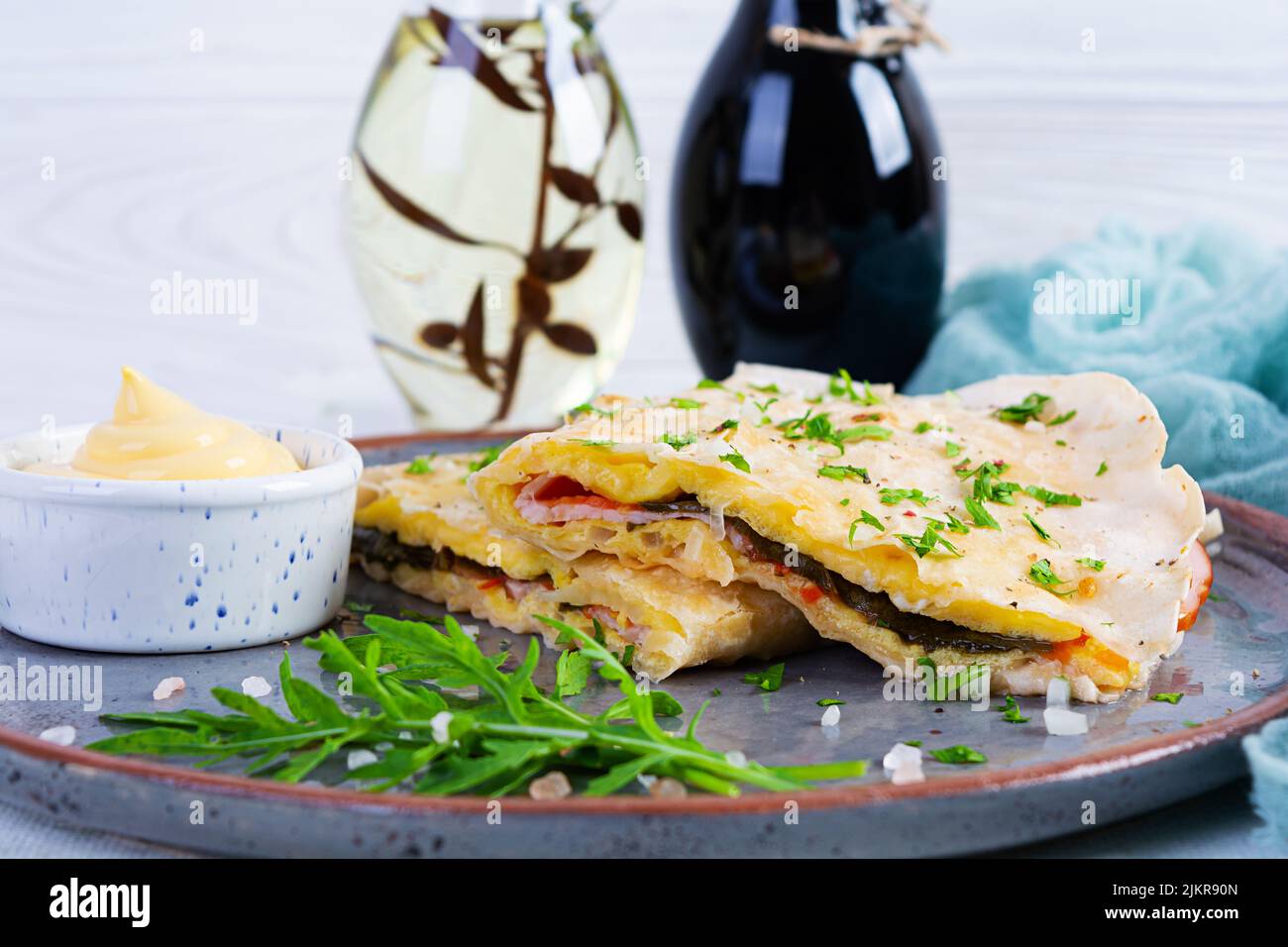 Fried pita bread with scrambled eggs, tomatoes, meat and cheese. Stuffed lavash Stock Photo