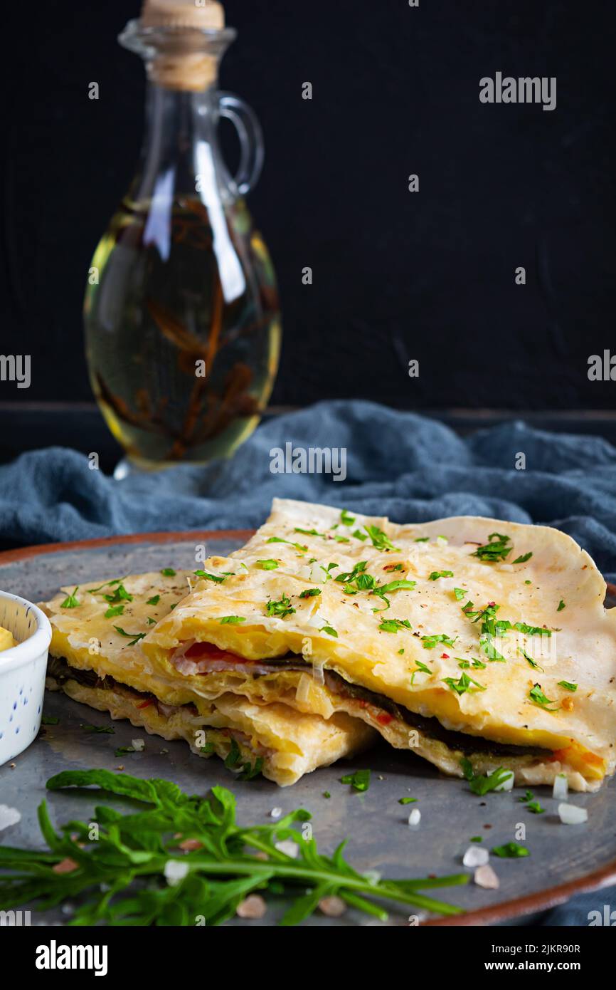 Fried pita bread with scrambled eggs, tomatoes, meat and cheese. Stuffed lavash Stock Photo