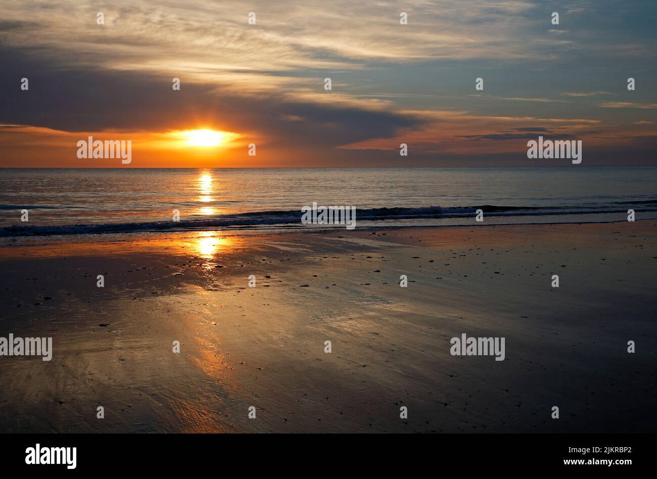 A view of a sunrise over the sea with reflections on the Norfolk coast at Cart Gap, Happisburgh, Norfolk, England, United Kingdom. Stock Photo