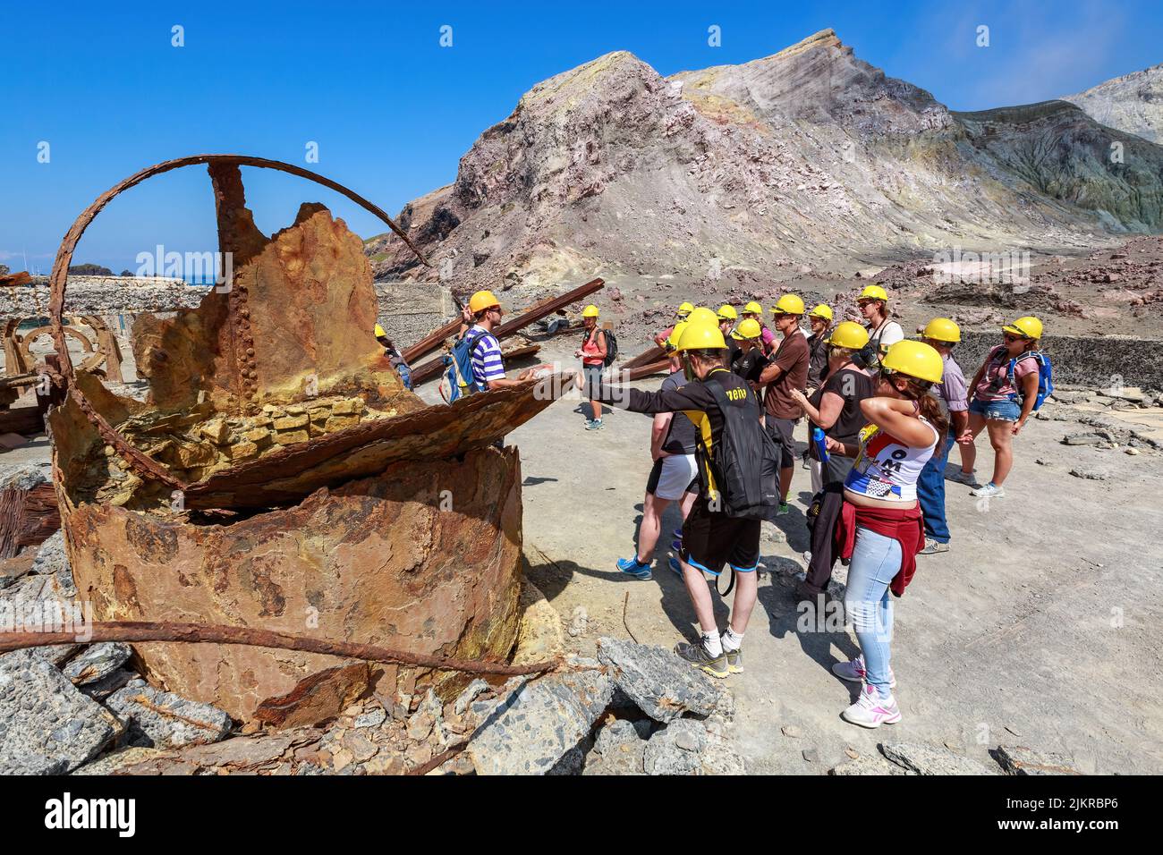 A tour group stands amid the ruins of an old sulfur processing plant on White Island, an active volcano in the Bay of Plenty, New Zealand Stock Photo