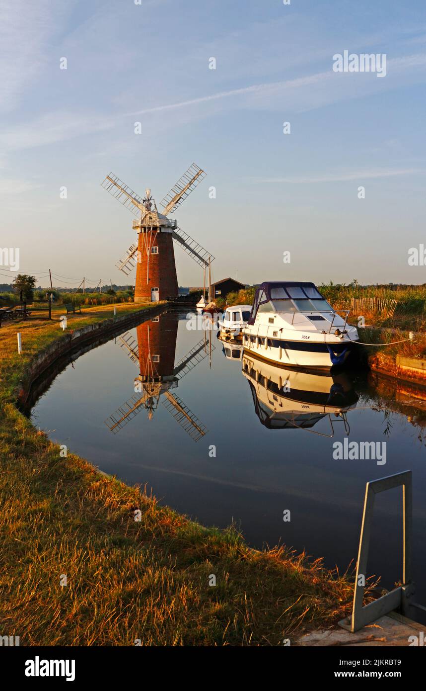 A view of Horsey Dyke with boat moorings and landmark Windmill and reflection on the Norfolk Broads at Horsey, Norfolk, England, United Kingdom. Stock Photo