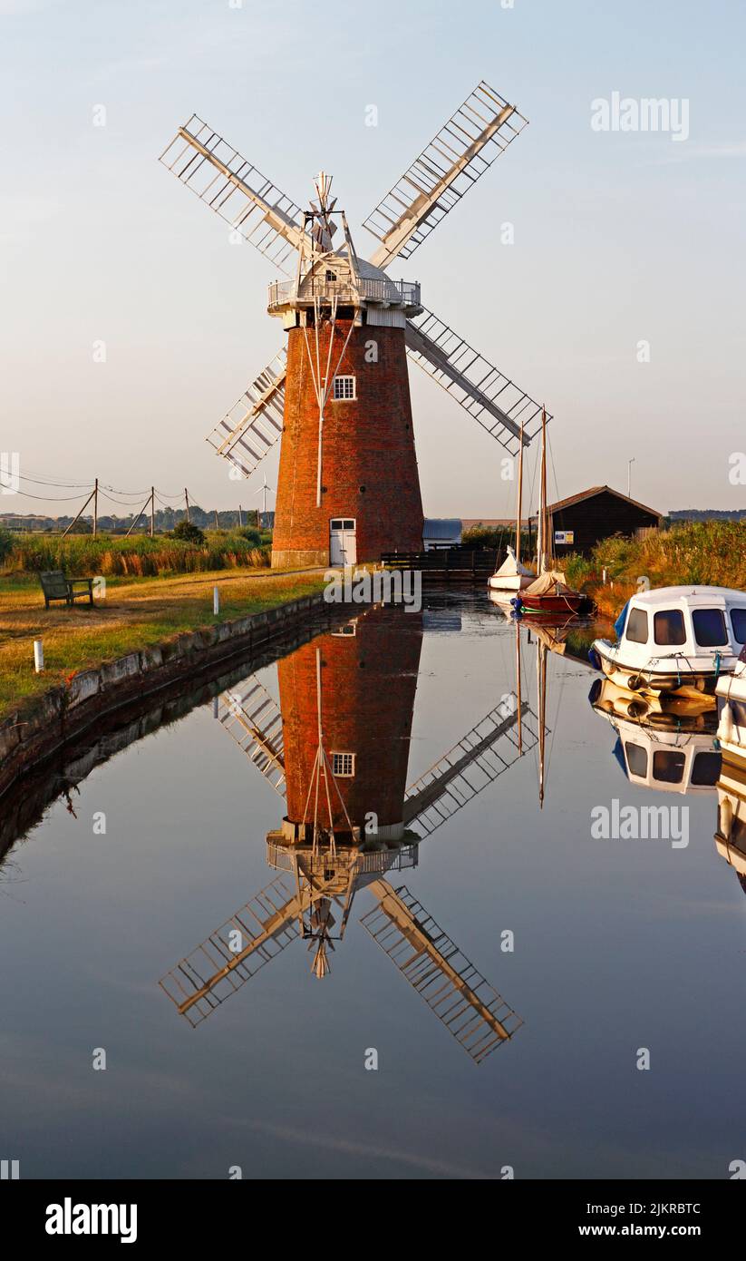 A view of Horsey Dyke with boat moorings and landmark Windmill and reflection on the Norfolk Broads at Horsey, Norfolk, England, United Kingdom. Stock Photo