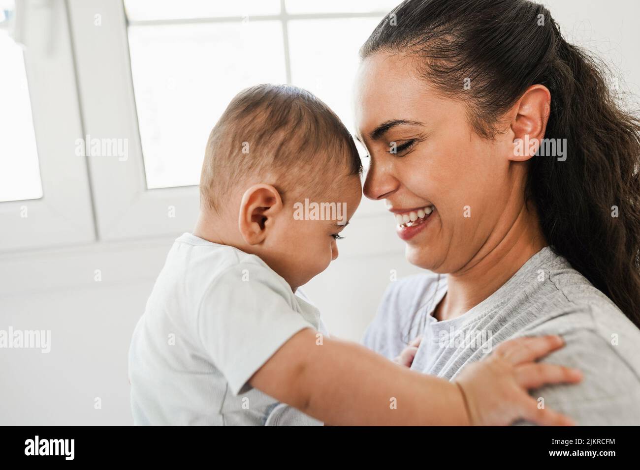 Young latin mom having fun with her son in bed at home Soft focus on
