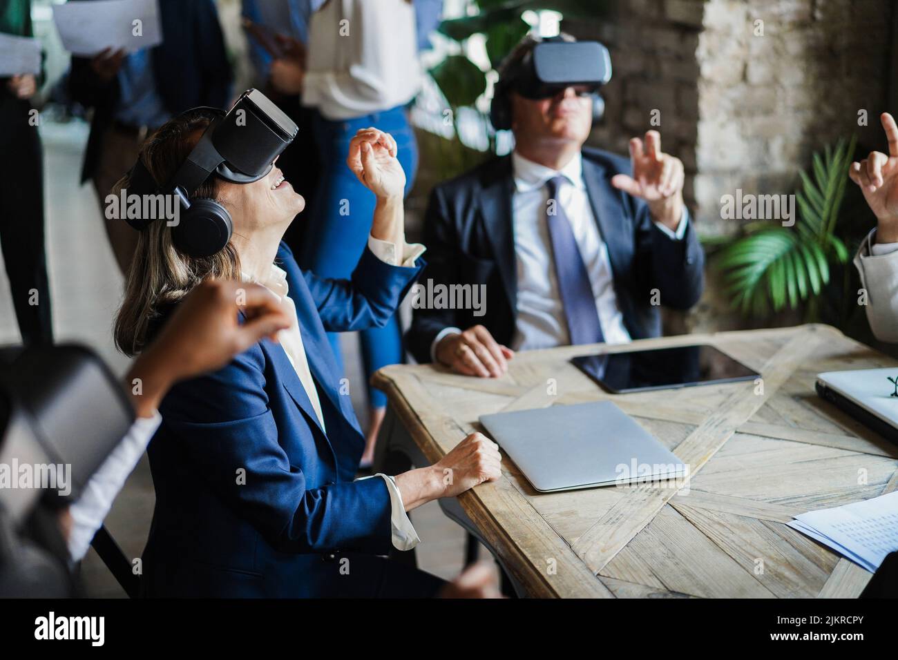 Business people wearing virtual reality goggles inside office - Focus on senior woman headset Stock Photo