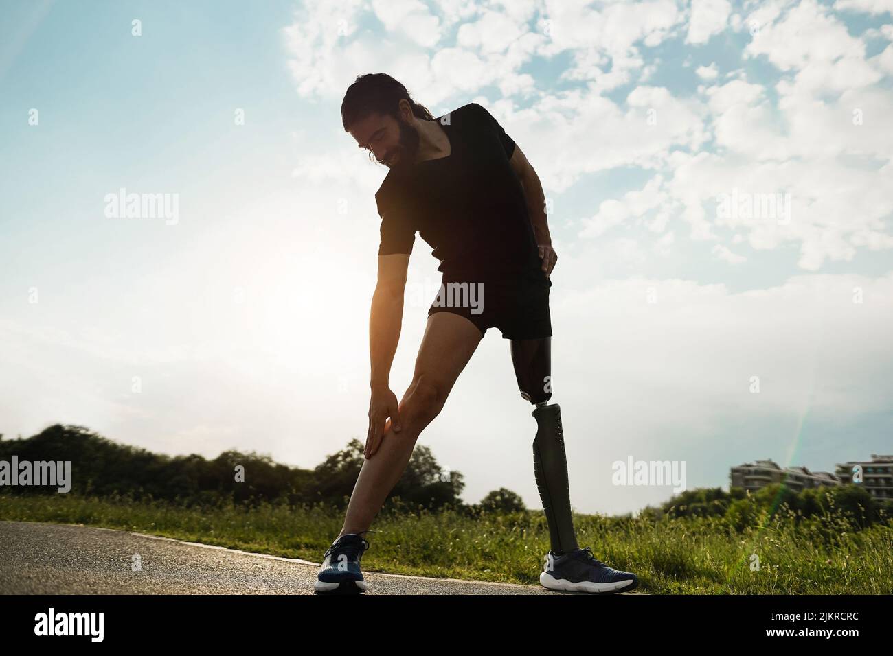 Young fit man with prosthetic leg doing stretching day routine outdoor - Focus on left hand Stock Photo