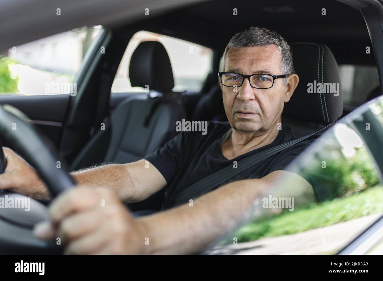 Happy senior in his 70s driving a car Stock Photo