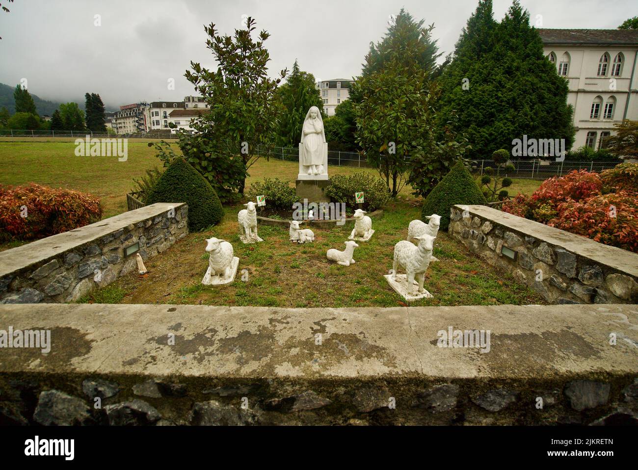 A Statue of Bernadette of Lourdes with sheep/lambs in Lourdes, France. Stock Photo