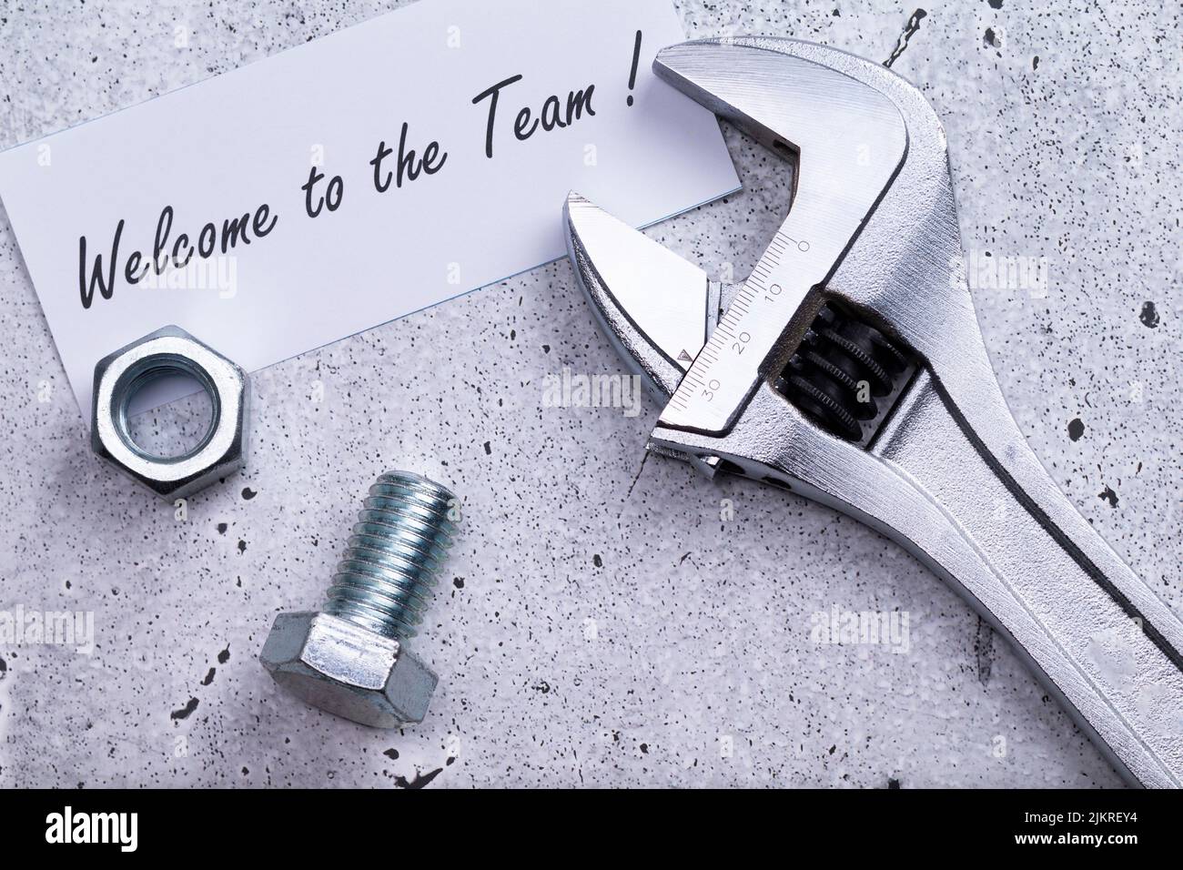 The photo shows a label with the words 'welcome to our team' with a wrench and srew on a grey background Stock Photo